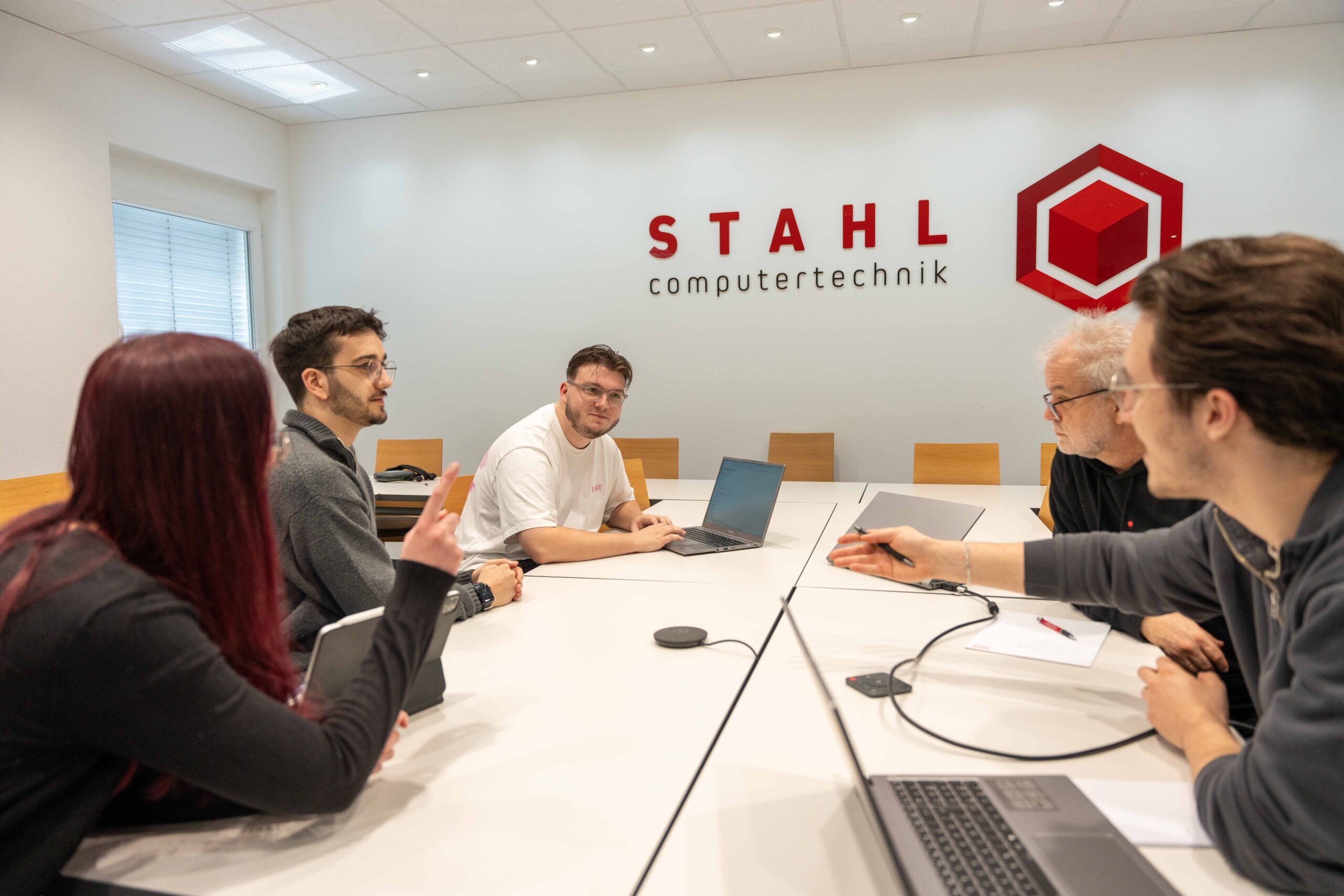 Ein Meeting in der Stahl GmbH mit 5 Mitarbeitern an einem Konferenztisch